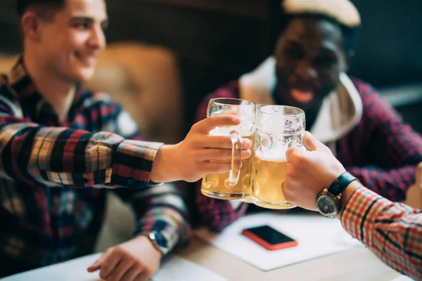 Salud, amigos míos. Tres hombres guapos son vítores taza, beber cerveza, celebrar la reunión y sonreír . — Foto de Stock