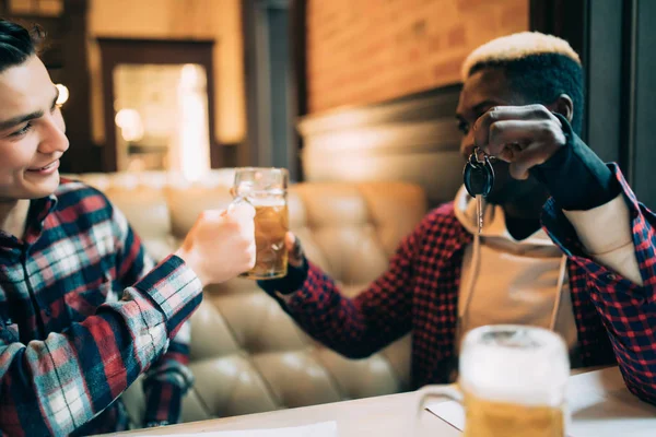 El joven afroamericano sostiene las llaves del auto y se niega a beber cerveza de su amigo en el bar. No beber y conducir . — Foto de Stock