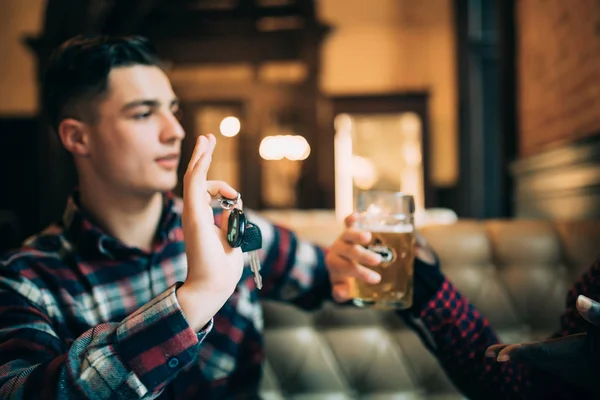 No beba ni conduzca. El joven sostiene las llaves del coche y se niega a beber cerveza de su amigo en el pub. — Foto de Stock