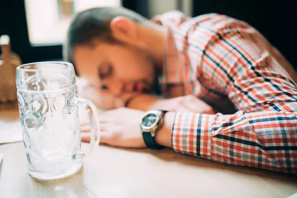 Wieder betrunken. Betrunkener männlicher Kunde lehnt am Tresen und schläft, während Glas mit Bier neben ihm steht — Stockfoto