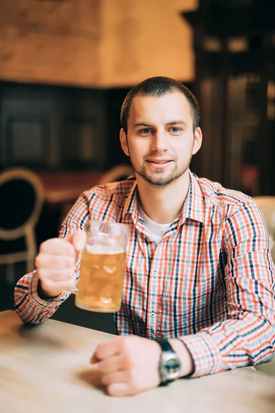 Um homem a beber cerveja. Jovem bonito bebendo cerveja enquanto estava sentado no pub — Fotografia de Stock