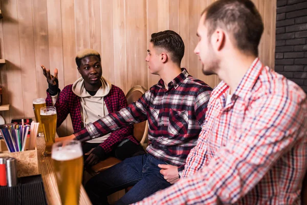 Alegre velhos amigos multirraciais se divertindo e bebendo cerveja rascunho no bar balcão no pub . — Fotografia de Stock