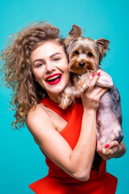 Kameraya bakarak ve Yorkshire terrier izole görünümü yeşil zemin üzerine tutarak gülümseyen genç çekici kadın portresi.