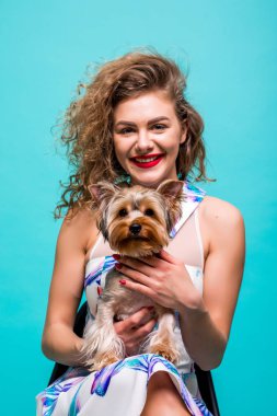 Renk arka plan üzerinde izole onun terrier köpek tutan gülümseyen bir kıvırcık kadın portresi