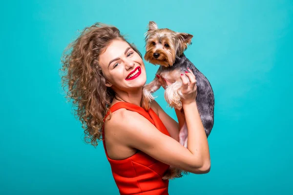 Szép nő, a piros dresss, Yorkshire terrier kutya ad puszit elszigetelt color background — Stock Fotó