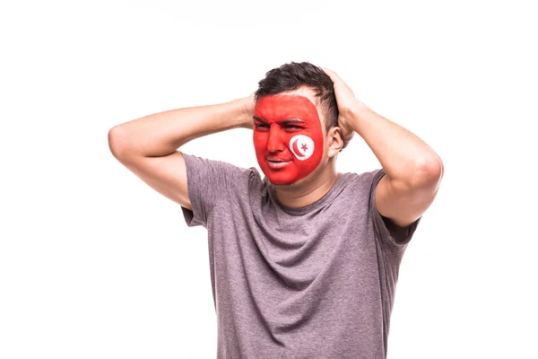 Perdedor molesto apoyo del ventilador de la selección nacional de Túnez con la cara pintada aislado sobre fondo blanco — Foto de Stock