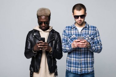 Hoş sohbet ve işbirliği kavramı. Gri arka plan üzerinde izole telefon bağımlılığı ile iki karma yarış arkadaş