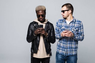 Hoş sohbet ve işbirliği kavramı. Gri arka plan üzerinde izole telefon bağımlılığı ile iki karma yarış arkadaş