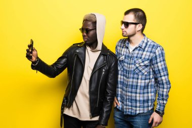 İle hareket eden telefon fotoğraf makinesi üzerinde sarı arka plan izole selfie alarak iki en iyi çok ırklı arkadaş. İki en iyi arkadaş karışık ırk almak selfie Sarı zemin üzerine