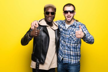 Genç erkekler başparmak yukarıya üzerinde sarı arka plan izole karışık yarış en iyi arkadaşlarım