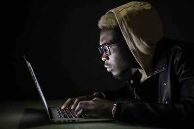 Hacker saldırı sunucunun içinde belgili tanımlık karanlık. Afro Amerikan hacker kesmek--dan laptop sunucu karanlıkta