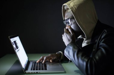 Internet üzerinden bir bilgisayar masası geceleri Afro Amerikalı adam oturur. Gece internette sörf. Gece bir masada oyun oturur ve çerezleri onun elinde olan bir bilgisayar yakın ekrana görünüyor