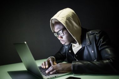 Internet üzerinden bir bilgisayar masası geceleri Afro Amerikalı adam oturur. Gece internette sörf. Gece bir masada oyun oturur ve çerezleri onun elinde olan bir bilgisayar yakın ekrana görünüyor