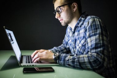 Bilgisayarda çalışma gece karanlık ofisinde bir genç adam. Tasarımcı sonradan içinde çalışır. Genç bir adam bilgisayar gece oturur.