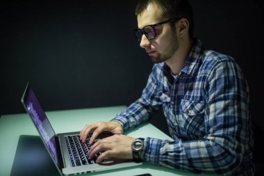 Bilgisayarda çalışma gece karanlık ofisinde bir genç adam. Tasarımcı sonradan içinde çalışır. Genç bir adam bilgisayar gece oturur.