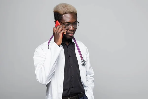 Csinos afroamerikai orvos beszél a mobiltelefon elszigetelt szürke — Stock Fotó