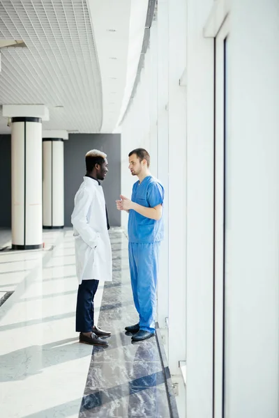 Medical mixed race staff having Discussion In Modern Hospital Corridor