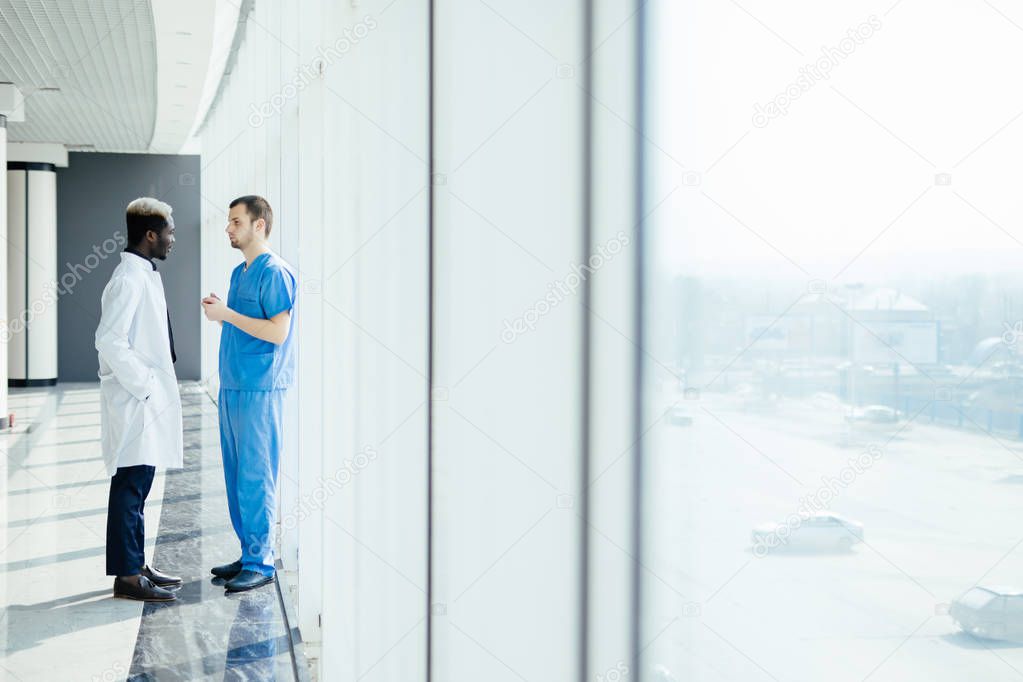 Medical mixed race staff having Discussion In Modern Hospital Corridor