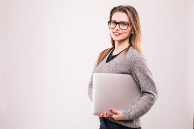 Dizüstü bilgisayar gri arka plan üzerinde tutarak ve kameraya bakarak mutlu bir casual kadın portresi