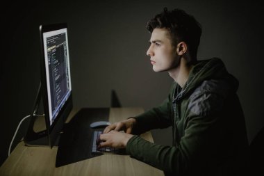Yakışıklı erkek programcı, bu kişi, hacker, bilgisayar pc önünde karanlık odada internet üzerinde çalışır