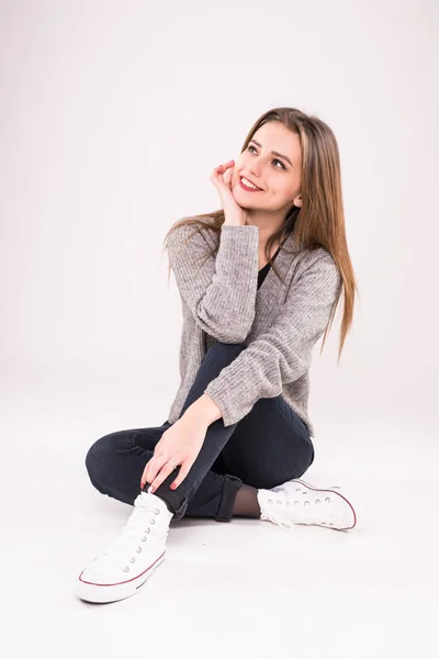 Щаслива дівчина-підліток сидить на підлозі ізольовано на білому тлі — стокове фото