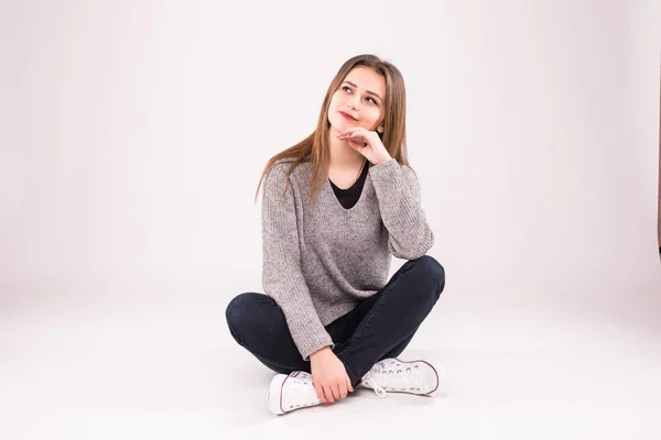 Feliz adolescente sentada en el suelo aislada sobre un fondo blanco —  Fotos de Stock