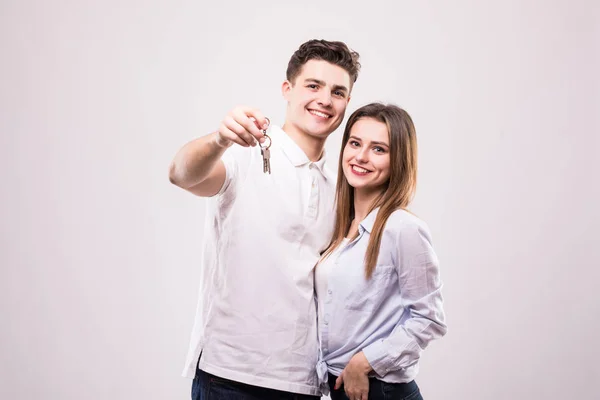 Χαρούμενη νεαρό ζευγάρι με ένα ζεύγος κλειδιών που απομονώνονται σε λευκό — Φωτογραφία Αρχείου