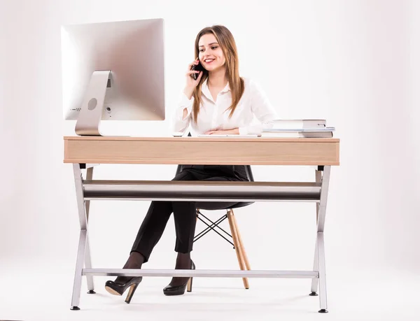 Молода професійна бізнес-леді працює за столом, розмовляючи по телефону ізольовано на білому тлі — стокове фото