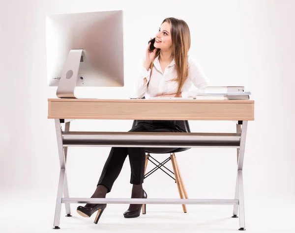 Beyaz arka plan üzerinde izole telefonda konuşan onun masasında çalışan genç profesyonel iş kadın — Stok fotoğraf