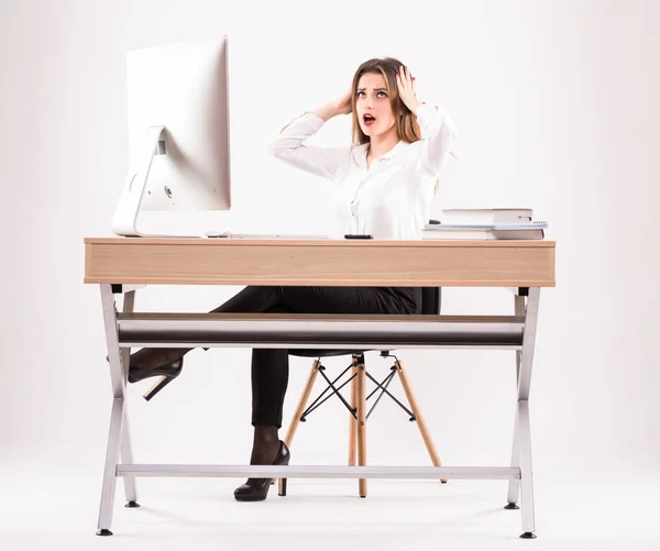 Comprimento total retrato de uma jovem empresária surpreso sentado à mesa com pc sobre fundo branco — Fotografia de Stock