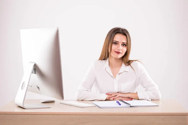 Giovane donna seduta davanti ad un pc alla scrivania, isolata su sfondo bianco — Foto Stock