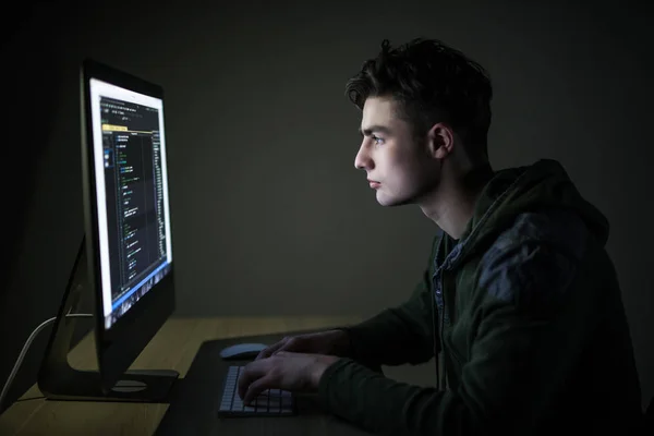 Молодой хакер в темноте нарушает доступ к краже информации и заражает компьютеры и системы. концепция хакерства и кибертерроризма — стоковое фото