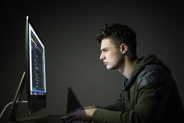 Young man hacking server in dark room. Young man programm code on pc in dark room. White hacker. — Stock Photo, Image