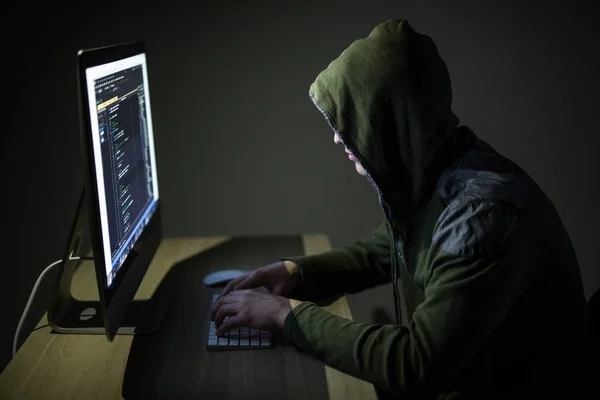 Computer hacker in hood working in dark room code on pc and hack networks — Stock Photo, Image