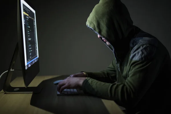 Hooded computer hacker stealing information with pc in Dark room background — Stock Photo, Image
