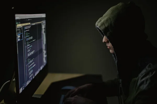 Hooded computer hacker stealing information with pc in Dark room background — Stock Photo, Image