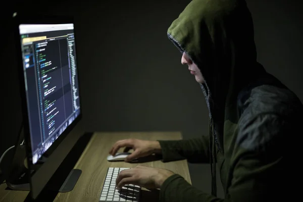 Hooded computer hacker stealing information with pc in Dark room background — Stock Photo, Image