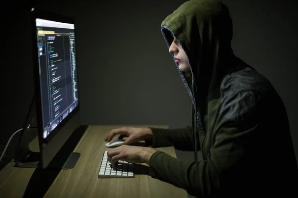 戴着帽衫的人在暗室里窃听服务器。年轻人黑客服务器或白色黑客保护网络 — 图库照片