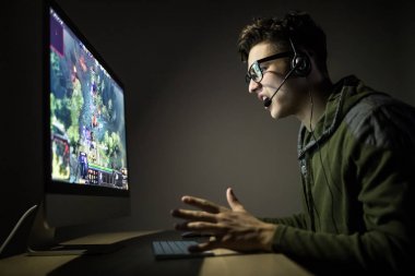 teknoloji, oyun, eğlence, oyun ve insanlar kavramı - kulaklık ve gözlük evde oyun oynarken ve playthrough veya anlatım video akarsu pc bilgisayar ile mutlu genç adam
