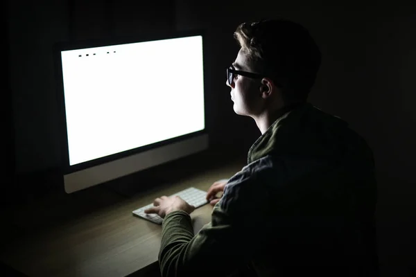 Guapo programador masculino, persona de TI, hacker, trabaja en la computadora en Internet en cuarto oscuro delante de la PC — Foto de Stock