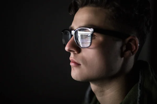 Közelkép a férfi arcát. Szem, komoly fiatal ember használ saját táblaszámítógépén fekete felni szemüvegét. Képernyő és ujj, ami tükrözi az üveg — Stock Fotó