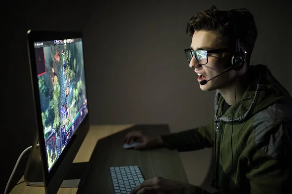 Nacht spelen. jonge gamer in hoofdtelefoons en bril met behulp van de computer voor het spelen van game thuis in de nacht — Stockfoto