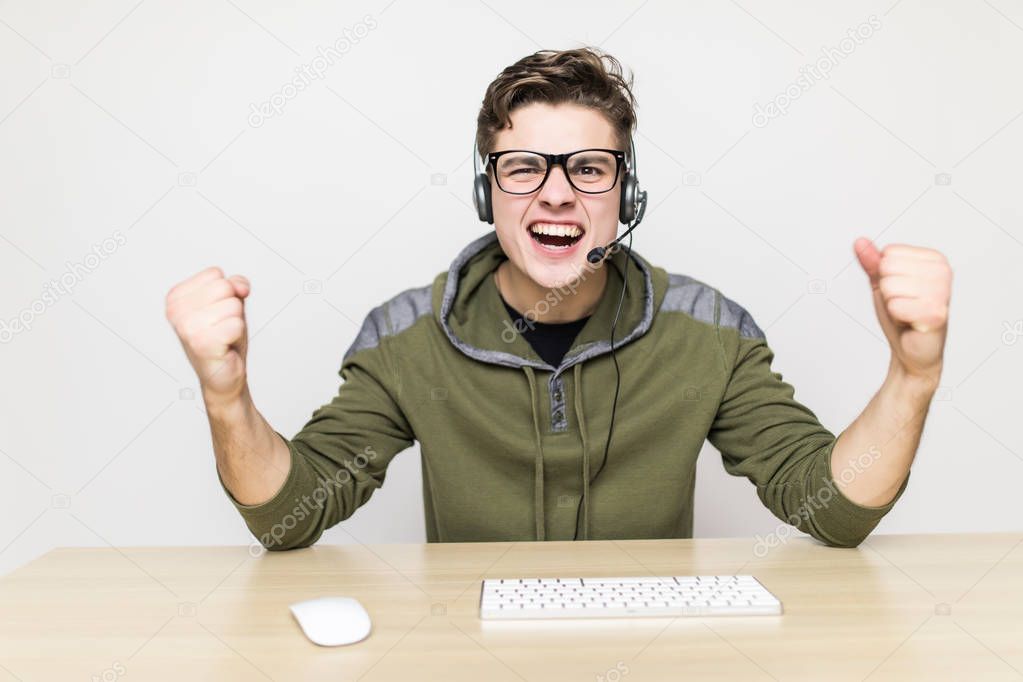 technology, gaming, entertainment, let's play and people concept - happy young man in eyeglasses with headset playing and winning computer game at home