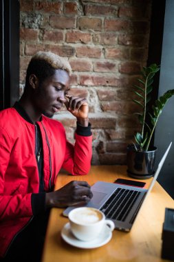 Afro laptop kafede kahve ile çalışma ile gülümseyen bir adam portresi