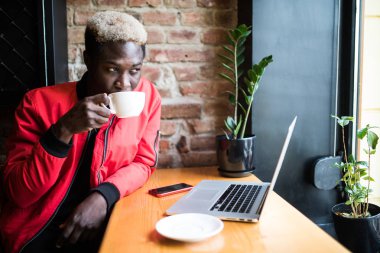 Bir ceket kahve içmek ve iş üstünde a laptop Afro-Amerikan bir adam portresi