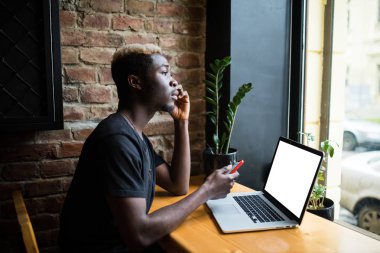Yan portre için kopya alanı kafede beyaz ekran ile bir genç afro Amerikalı adam çalışma dizüstü
