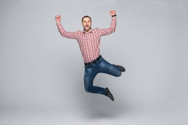 Dikey görüntü mutlu adam tişört ve kot hangi studio beyaz arka plan üzerinde atlama