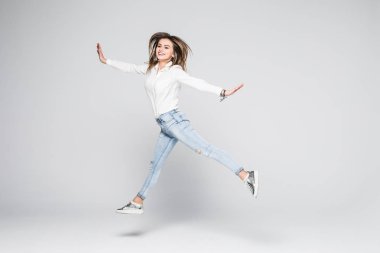 mutluluk, özgürlük, güç, hareket ve insanlar kavramı - gülümseyen genç kadın ile yükseltilmiş yumruklarını havada beyaz arka plan üzerinde atlama