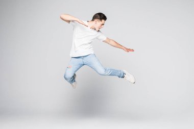 Neşeli genç adam beyaz arka planda atlıyor