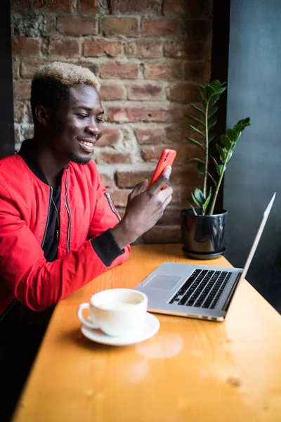 Joven afroamericano hombre hacer videollamada a través de aplicación desde el teléfono en la cafetería — Foto de Stock